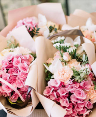 Ramos de flores en tonos rosados y blancos envueltos en papel kraft