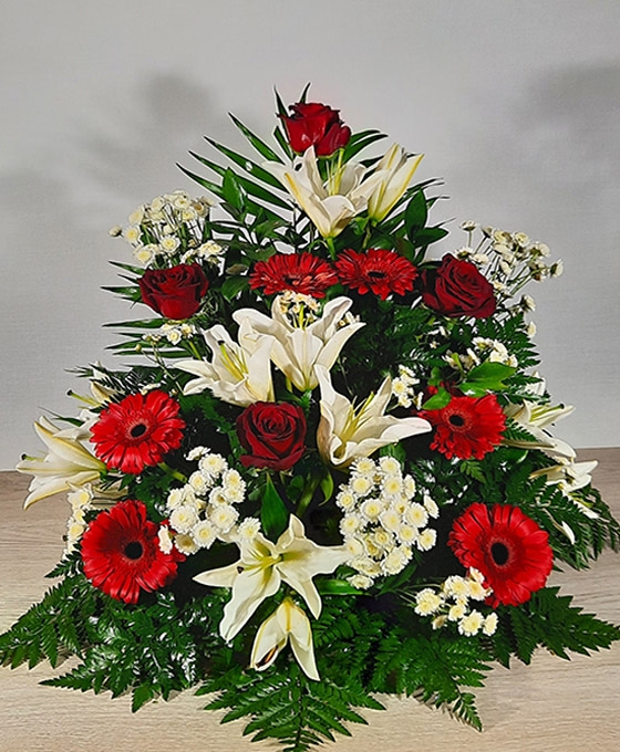 Centro de flores funerarias con gerberas y rosas rojas y margaritas y liliums blancas