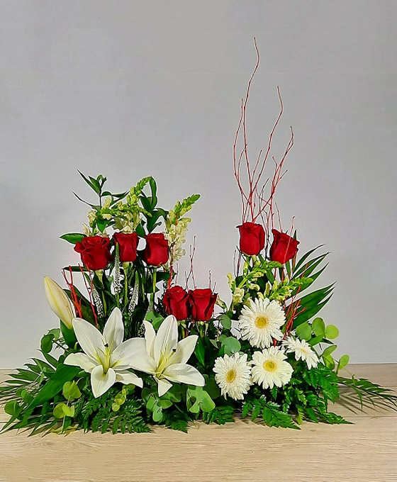 Centro funerario con forma de lágrima con rosas rojas y liliums y gerberas blancas