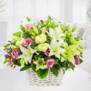 Cesta de flores blancas, verdes y rosadas en cesta de mimbre