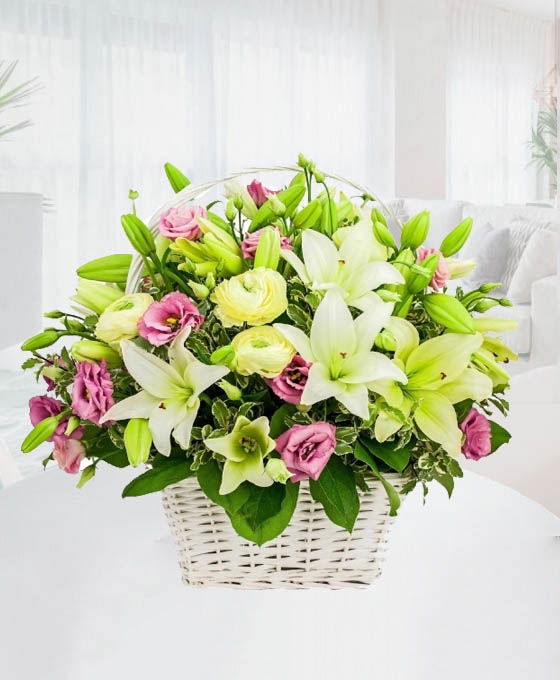 Cesta de flores blancas, verdes y rosadas en cesta de mimbre