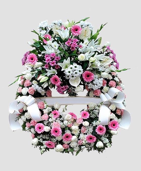 Corona de flores funerarias en tonos rosados y blancos