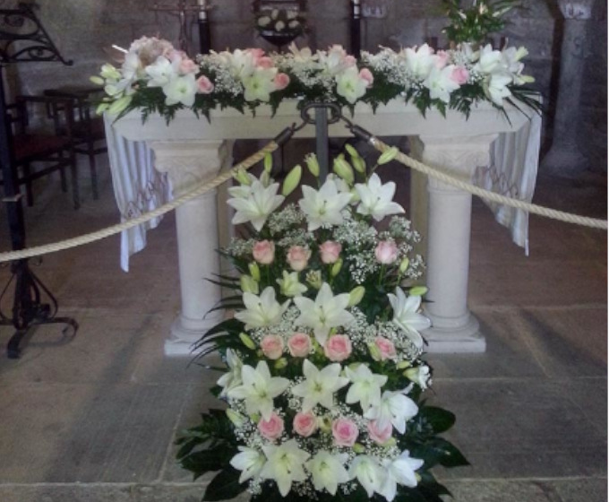 Decoración con centro de flores blancas y rosadas en presbiterio